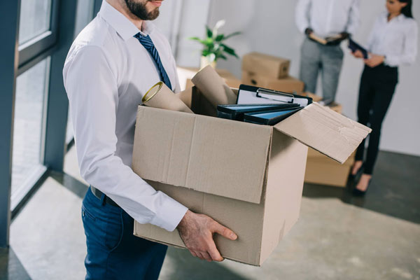 Hombre llevando una caja realizando mudanza de oficina.